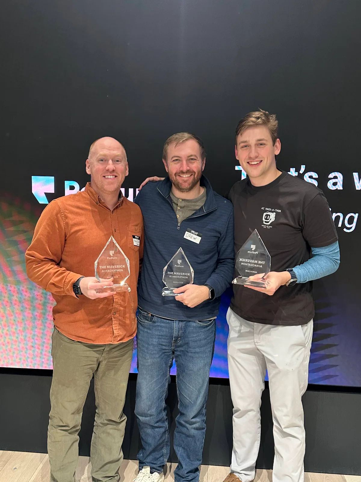 Granite and his two AIMy teammates holding The Maverick trophies at the Podium AI Hackathon